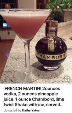 a pink drink sitting next to a bottle on top of a counter