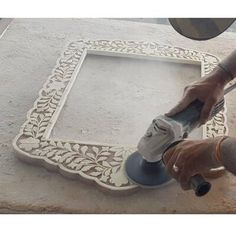 a man using a power tool to cut out a decorative tile border on a wall