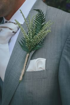 a man in a gray suit with a boutonniere on his lapel