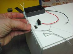 a hand is holding the wires that are connected to an electronic device on top of a box