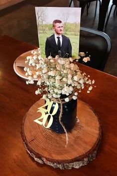 a wooden table topped with a vase filled with flowers and a card on top of it