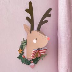 a deer head mounted to the side of a pink wall with christmas decorations around it