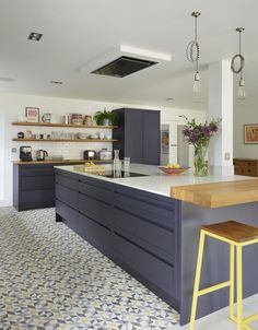 a kitchen with an island and yellow stools in the center, surrounded by gray cabinets