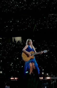 a woman in a blue dress holding a guitar