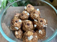 a glass bowl filled with cookies and marshmallows on top of a wooden table