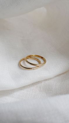 two gold rings sitting on top of a white cloth