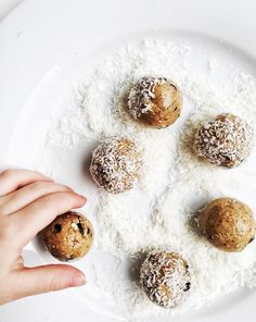 a white plate topped with four balls of doughnuts covered in powdered sugar