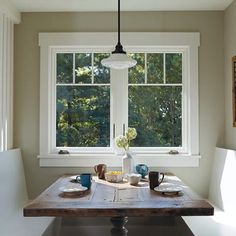 a wooden table sitting in front of two windows