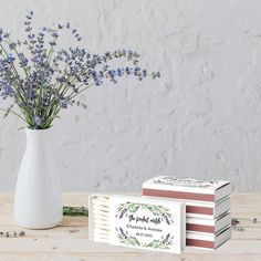 lavender flowers in a white vase next to two matchboxes