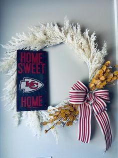 a football themed wreath hangs on the wall next to a sign that reads, home sweet home