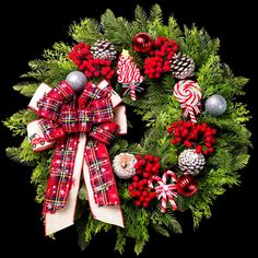 a christmas wreath decorated with candy canes, pine cones and other holiday decorations on a black background