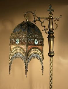 an ornate lamp is hanging on the wall next to a light pole with a blue glass beaded shade