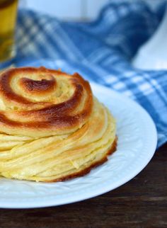 a stack of pancakes sitting on top of a white plate next to a glass of beer