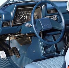 the interior of an old car with blue leather seats and dash board, steering wheel and gauges