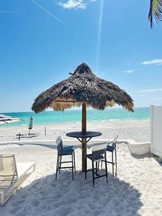 an umbrella on the beach with chairs and tables