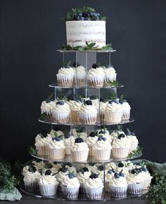 a tiered cake with cupcakes and berries on it