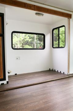 an empty room with wood flooring and windows in the wall to the left side