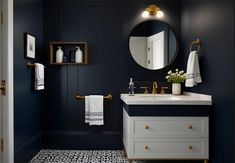 a white sink sitting under a bathroom mirror next to a black and white tiled floor