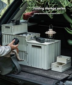 the back end of a car with storage containers in the trunk and someone holding a camera