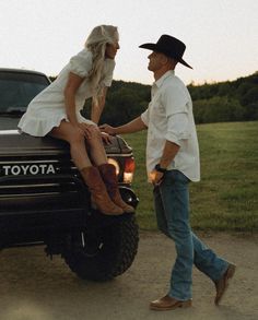 a man and woman are sitting on the back of a toyota truck in a field