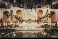 a stage set up for a wedding with chandeliers and flowers on the walls