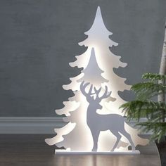 a lighted christmas tree with a deer standing next to it