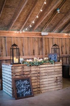 the barn wedding reception bar was made out of pallet boards and is decorated with greenery