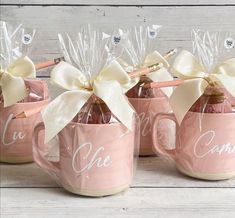 three pink mugs filled with candy and wrapped in white ribbon