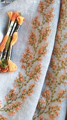 an orange flower is laying on top of some blue material with thread and scissors next to it