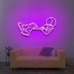 a living room with a couch and neon purple lighting on the wall above it is a drawing of a person laying down