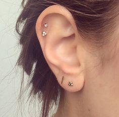 a close up of a person's ear with three piercings on it and one behind the ear