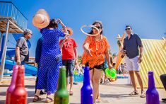 a group of people standing next to each other in front of colorful bottles and umbrellas