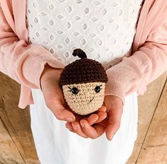 a person holding a small crocheted toy in their hands