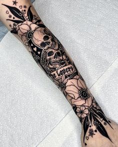 a person with a tattoo on their arm that has flowers and a skull in it