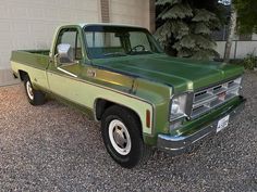 a green pick up truck parked in front of a garage