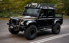 a black land rover is driving down the road