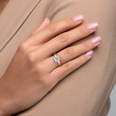 a woman's hand with a diamond ring on her left wrist, wearing a tan dress