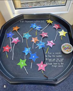 a black tray with colorful stars on it and numbers written on the side in white writing