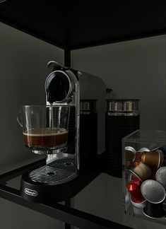 an espresso machine is sitting on a counter next to some cups and containers