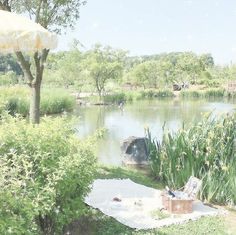 there is a picnic table and an umbrella in the grass by the water's edge