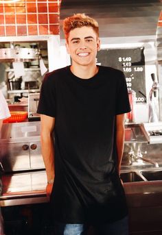 a young man standing in front of a kitchen counter with a smile on his face