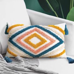 a white couch with a multicolored pillow on it and a blanket next to it