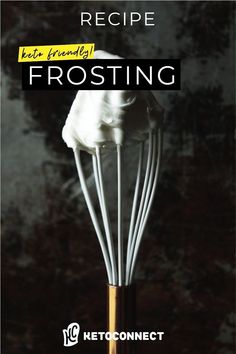 a whisk with white frosting in it on top of a wooden table