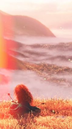 a woman sitting on top of a grass covered field next to a rainbow filled sky