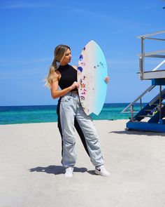 a woman holding a surfboard on the beach