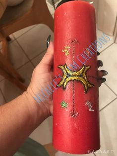 a hand holding a red candle with gold stars on it