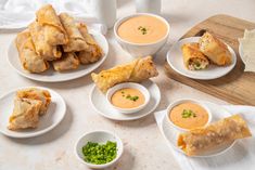 several plates of food on a table with dipping sauces and condiments around them