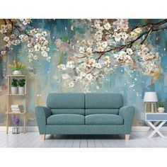 a blue couch sitting in front of a wall with white flowers and leaves on it