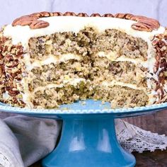 a cake with white frosting and pecans on top sitting on a blue plate