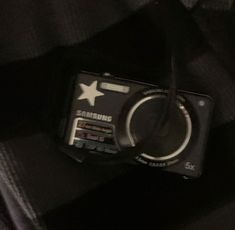 a black camera sitting on top of a persons lap in front of a person's shirt